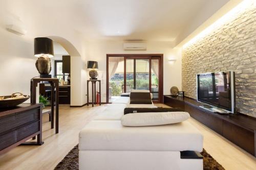 a living room with a white couch and a tv at Beautiful luxury villa located in Sardinia in Villasimius near the beaches in Gesturi