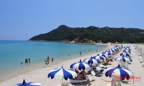 a beach with a bunch of blue and white umbrellas at Beautiful luxury villa located in Sardinia in Villasimius near the beaches in Gesturi