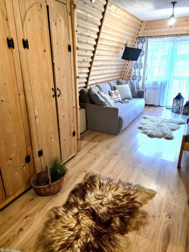 a living room with a couch and wooden walls at Grota zbójnicka apartament i pokoje in Gliczarów