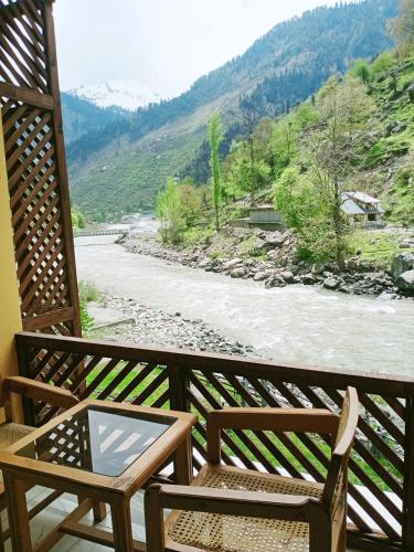a pair of chairs sitting on a balcony overlooking a river at Bela Resorts Naran in Nārān
