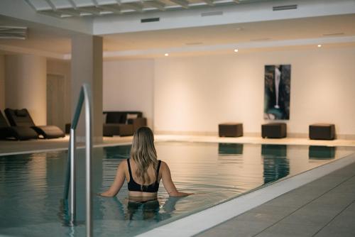 a woman is sitting in a swimming pool at Hotel Fronza - your hike & mountain home in Lutago