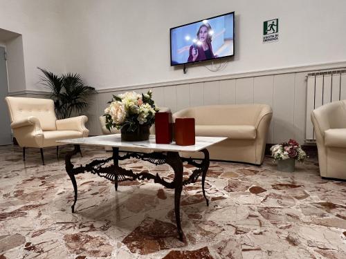 a waiting room with a table and a tv on a wall at Oasi Cuore in Castellammare di Stabia