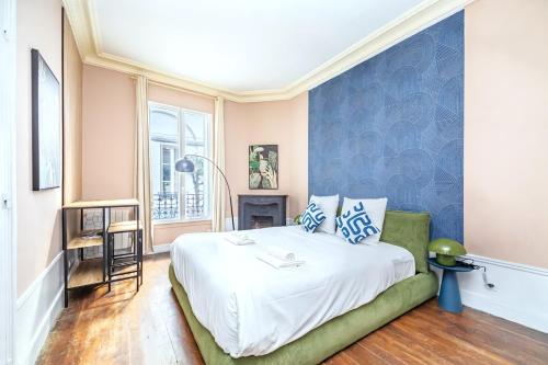 une chambre avec un lit avec un mur bleu dans l'établissement Studio confortable et pratique centre Paris 14-III, à Paris