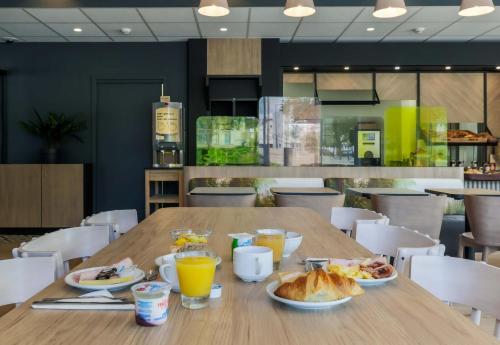 a wooden table with breakfast foods and drinks on it at B&B Hôtel Thionville Centre Gare Porte du Luxembourg A31 in Thionville