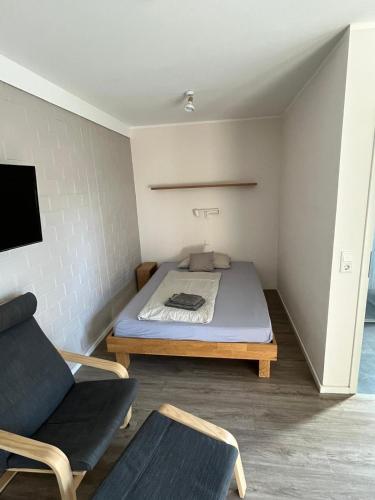 a small bedroom with a bed and a chair at Hempen Fied Gästehaus - Apartment 3 in Bad Zwischenahn