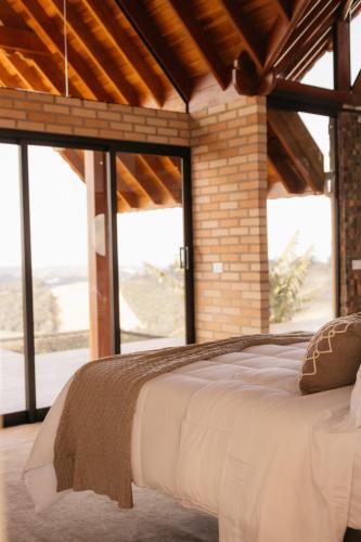a large bed in a room with large windows at Chalé Além do Horizonte in Bom Repouso
