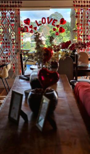 a table with flowers and a window with the word love at Recanto dos Moinhos - Boutique Hotel in Campos do Jordão