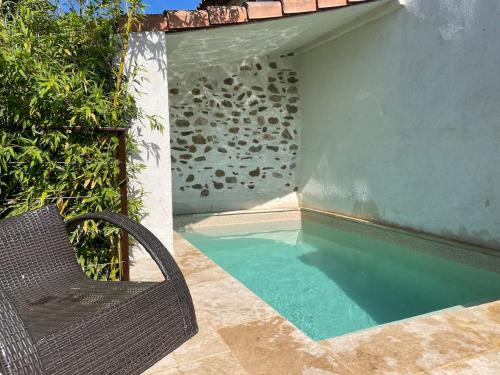 - une chaise en osier près de la piscine dans l'établissement Charmante maison de hameau, à La Londe-les-Maures