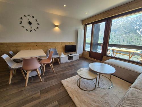 - un salon avec une table, des chaises et une horloge dans l'établissement Tignes: Beau 2 Pièces Cabine, 4 Pers, Face aux Pistes, Balcon, WIFI - FR-1-502-598, à Tignes