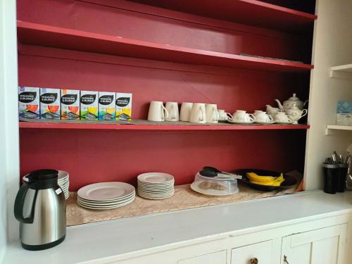 a cupboard filled with plates and cups and dishes at Andy's Blue House in Charlottetown