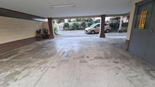 an empty parking lot with a car parked in a garage at ビジネス旅館 錦荘 - Nishiki Guest House in Kadoma