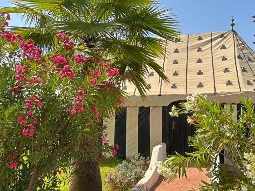 a building with a palm tree and pink flowers at Les Jardins D'issil in Marrakech