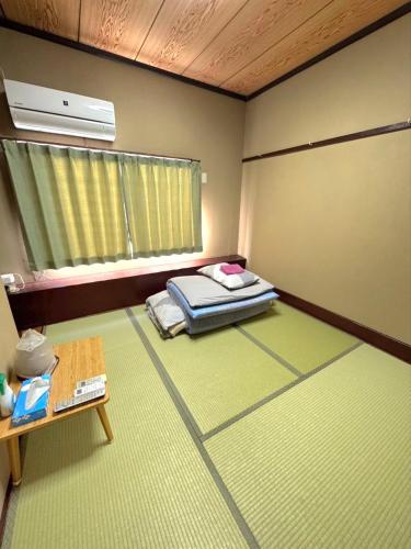 a room with a bed and a window and a table at ビジネス旅館 錦荘 - Nishiki Guest House in Kadoma
