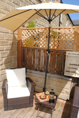 an umbrella on a patio with a chair and a table at Rosemary cottage -Your Cozy Countryside Escape, Matlock in Matlock