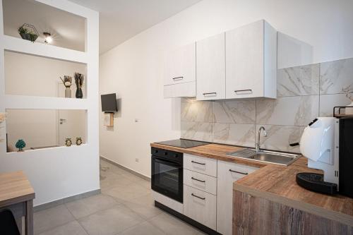 a kitchen with white cabinets and a sink at Piccolina Milazzo Mini Apartment - Casa Vacanze - in Milazzo