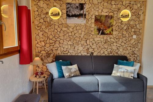 - un canapé bleu dans une chambre avec un mur en pierre dans l'établissement Estatico 2 - Apartment in chalet 70 m2 Garden level with 2 bedrooms, à Névache