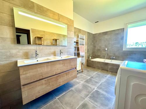 une salle de bain avec deux lavabos, une baignoire et un miroir dans l'établissement Grande maison au cœur de l'Ardèche 12 personnes, à Villeuneuve-de-Berg