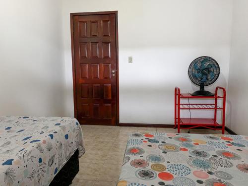 a bedroom with a bed and a red chair and a door at Casa com Wi-Fi proximo a Ilha de Itaparica in Ponta da Areia