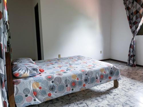 a bedroom with a bed with a flowered blanket at Casa com Wi-Fi proximo a Ilha de Itaparica in Ponta da Areia