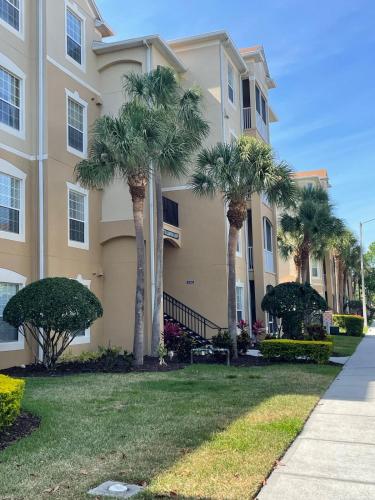 a building with palm trees in front of a yard at Family Friendly II in Orlando