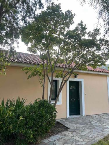 a small house with a black door and a tree at Anabelis studios & apartments in Katelios