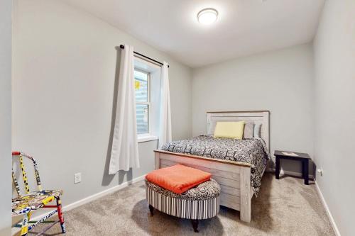 a bedroom with a bed and a window and a chair at Oak Street Beach House in New Buffalo