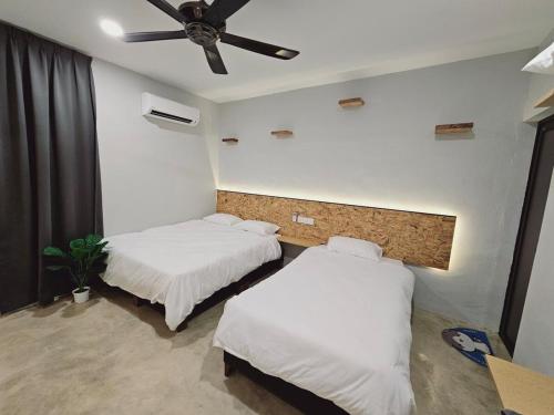 two beds in a room with a ceiling fan at Gold Plus Homestay 5970 in Kuantan