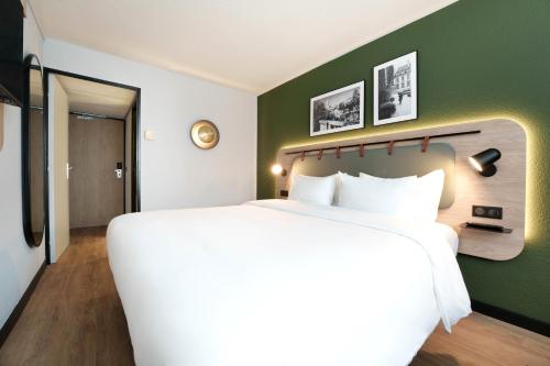 a large white bed in a room with a green wall at Campanile Paris Ouest - Pont de Suresnes in Suresnes