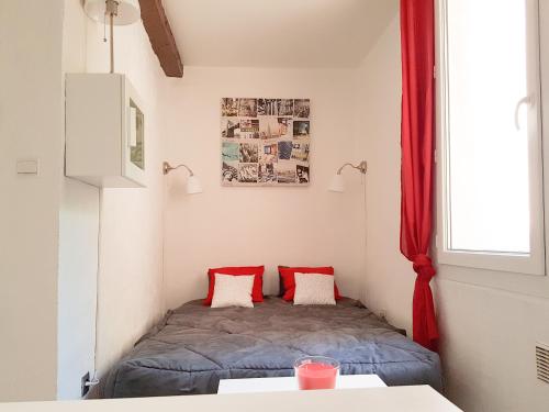 Cette petite chambre comprend un lit avec des oreillers rouges. dans l'établissement Le panier centre historique de marseille, à Marseille