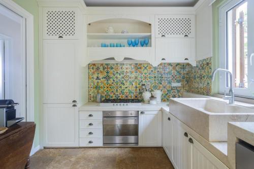 a kitchen with white cabinets and a sink at Villa Il Basto 8 by Massimo Villas in SantʼAmbrogio