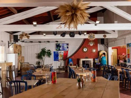un restaurant avec des tables et des chaises en bois et une cheminée dans l'établissement Camping 4 étoiles - Piscine - ccbbehe, à Saint-Cyprien