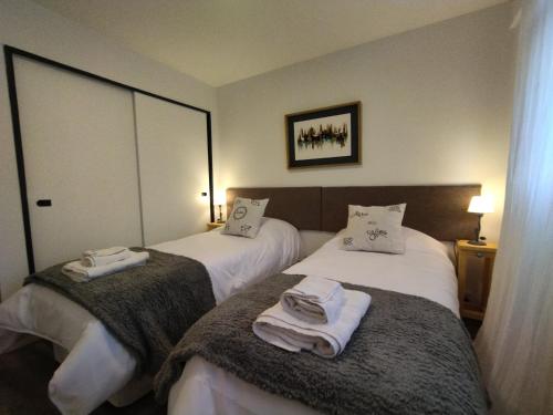 two beds in a hotel room with towels on them at Amado Sur Apartment in San Carlos de Bariloche