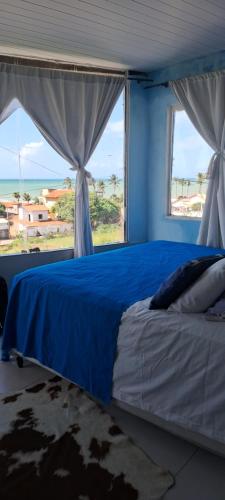 a bedroom with a blue bed with a large window at Vistamar Arco das Flores in Taíba
