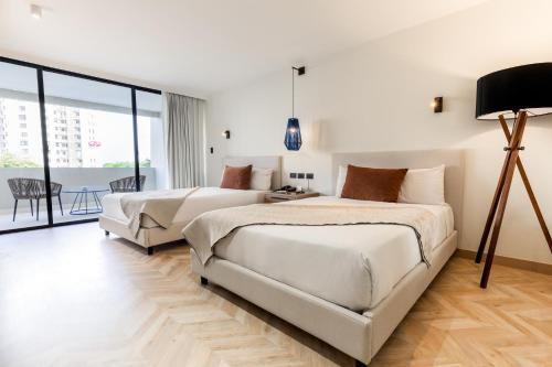 two beds in a white room with a balcony at Dominican Fiesta Hotel in Santo Domingo