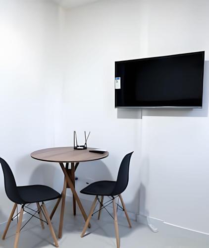 a table and two chairs and a television on a wall at Aptos Imperdíveis com Piscina Aquecida 2204 e 2304 in Rio de Janeiro