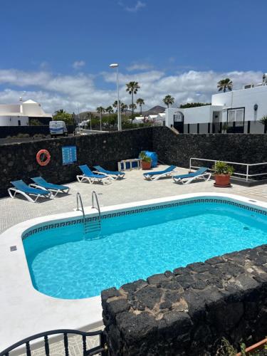 a swimming pool with blue water and lounge chairs at Paraíso Marino in Tías
