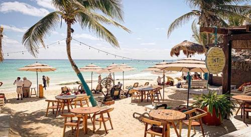 a beach with tables and umbrellas and the ocean at Bellooceano in Playa del Carmen