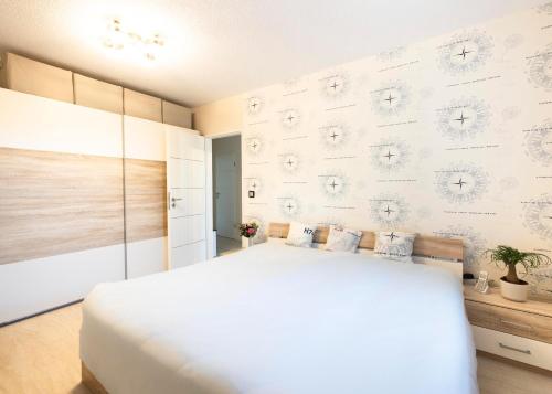 a bedroom with a white bed and a wall at Kleiner Garten Sauna und Hallenbad kostenlos Hund willkommen in Dorum-Neufeld