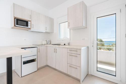 a white kitchen with white cabinets and a window at CrossRhodes Villas in Pefki Rhodes