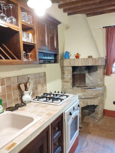 a kitchen with a stove and a stone fireplace at Castellare in Chiusdino