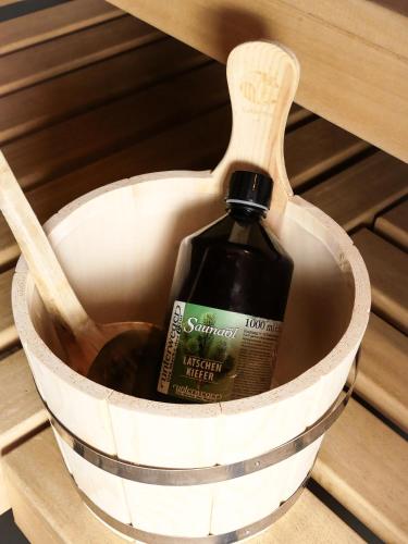 a bottle of wine in a bucket with a wooden spoon at Pension Posthansl in Heiterwang