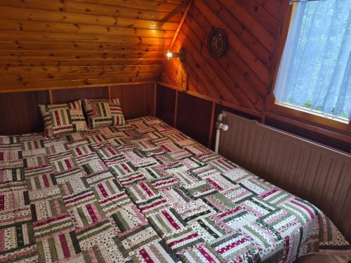 a bed in a room with a quilt on it at Chata v lese pri rieke Bela in Pribylina