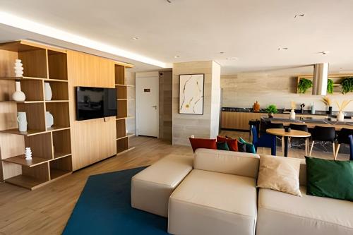 a living room with a white couch and a kitchen at LUXO 1603 Melhor Custo com Piscina Aquecida e WIFI in Rio de Janeiro