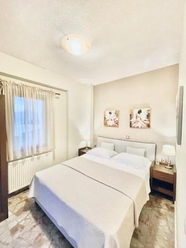 a bedroom with a large white bed and a window at Palamidi in Agia Paraskevi