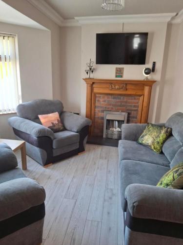a living room with two couches and a fireplace at Dark Hedges Cottage in Ballycastle