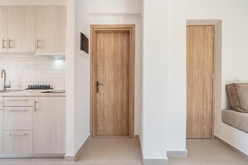 a kitchen with white walls and wooden doors at CrossRhodes Villas in Pefki Rhodes