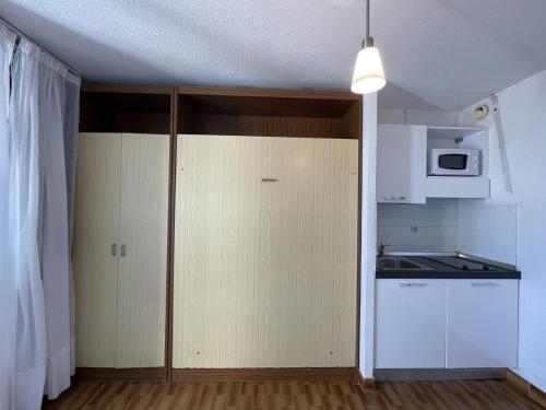 La cuisine est équipée de placards blancs et d'un four micro-ondes blanc. dans l'établissement Studio F32 Héliopolis - 2 personnes, au Cap d'Agde