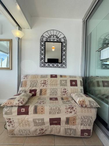 une chambre avec un lit et un miroir au mur dans l'établissement Héliopolis Studio F28 - 4 personnes, au Cap d'Agde