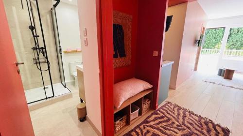 La salle de bains est pourvue d'une douche et d'un mur rouge. dans l'établissement Proche Palais Des Festivals, plage 5min - Palmazur Vacances, à Cannes