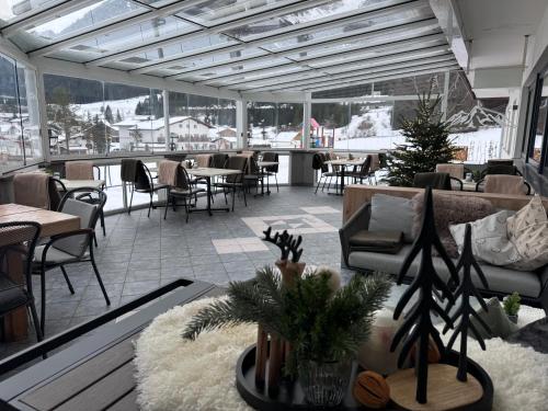 restauracja ze stołami i krzesłami w pokoju z oknami w obiekcie Pension Posthansl w mieście Heiterwang